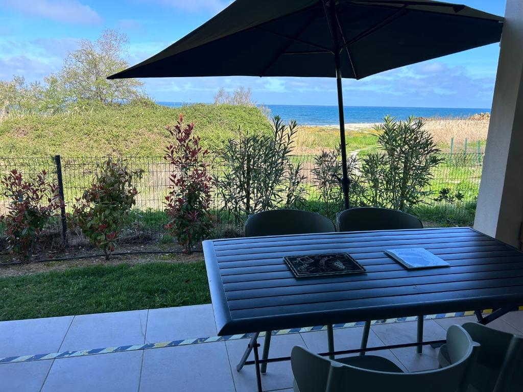 une table avec des chaises et un parasol sur une terrasse dans l'établissement Bravone 74- piscine en résidence-clim-wifi-pieds dans l'eau, à Linguizzetta