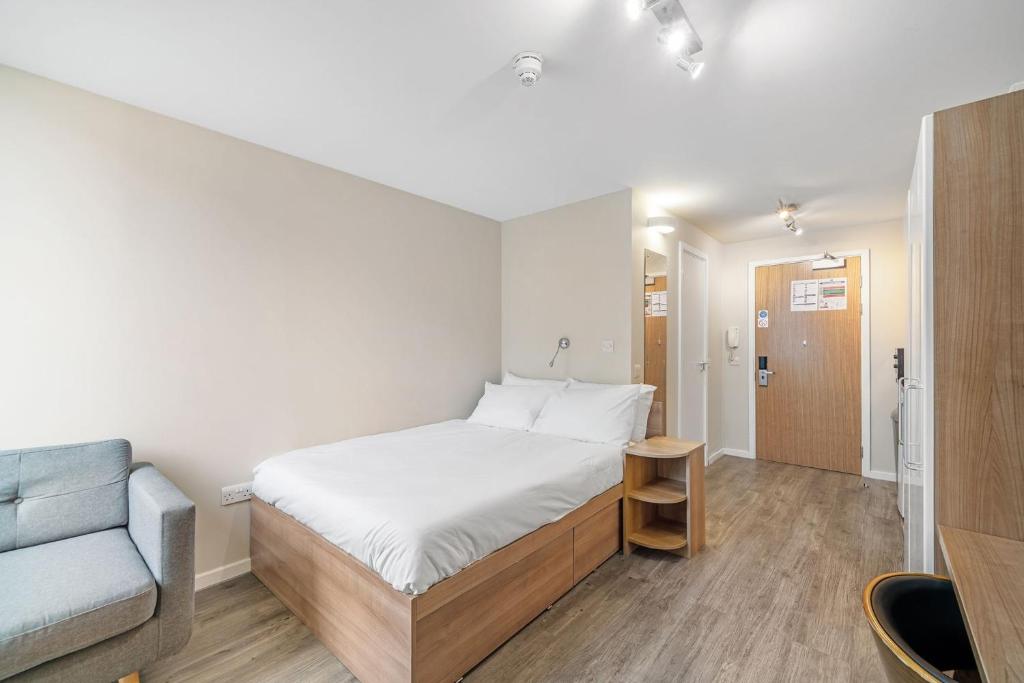 niewielka sypialnia z łóżkiem i kanapą w obiekcie Chic Studios and Apartments at Chapter South Bank in London w Londynie