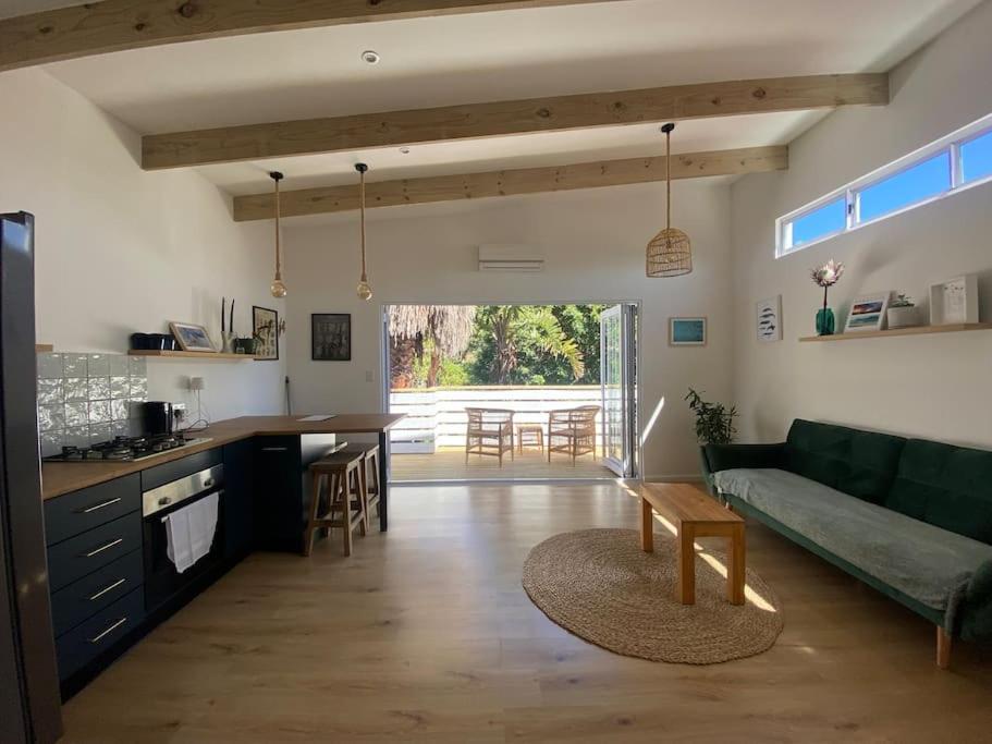 a kitchen and living room with a couch and a table at Tree House by the Ocean in Kommetjie
