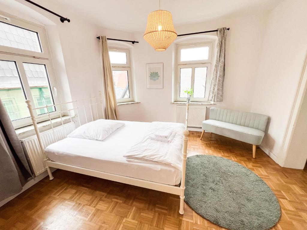 a bedroom with a bed and a chair and windows at Old Town Center Apartments in Kulmbach