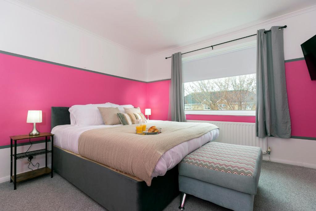 a pink bedroom with a large bed and a window at Park House in Durham