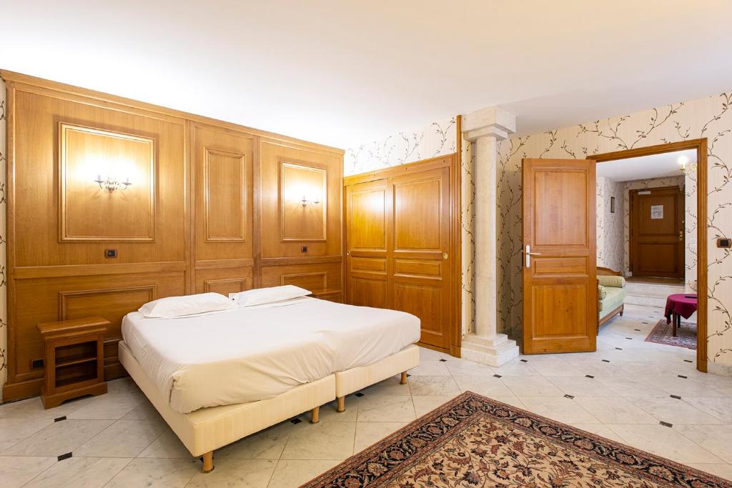 een slaapkamer met een groot wit bed en houten wanden bij Hotel Belle Epoque in Beaune