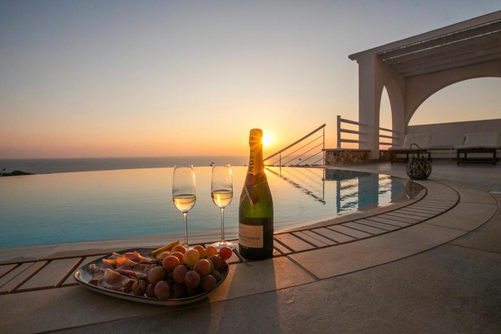 una botella de vino y un plato de fruta junto a la piscina en Villa Kyklamino - Unique Villa with stunning Seaview, en Klorakas
