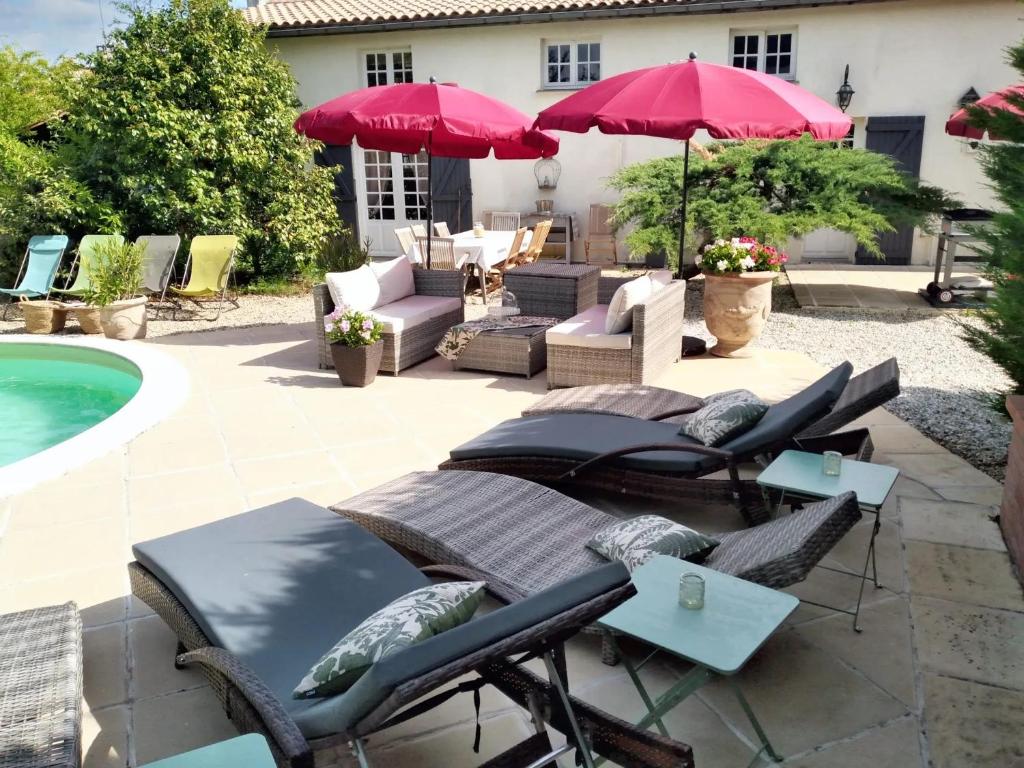 eine Terrasse mit Stühlen und Sonnenschirmen neben einem Pool in der Unterkunft Villa de 3 chambres avec piscine privee jardin clos et wifi a Arsac in Arsac