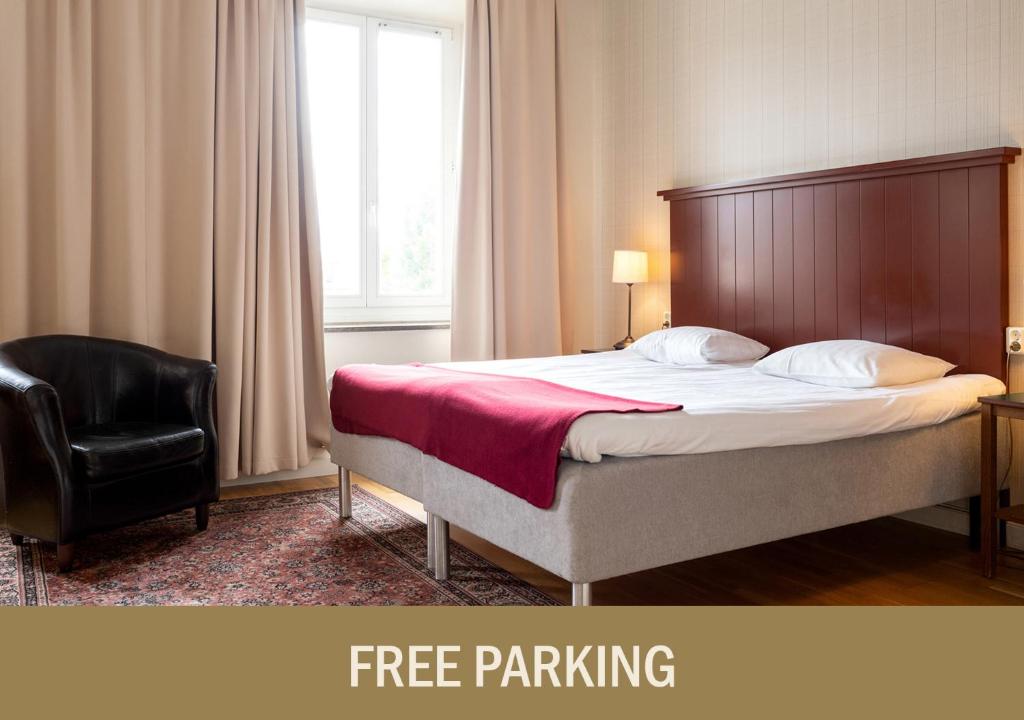 1 dormitorio con 1 cama y 1 silla negra en Hotel Bishops Arms Kristianstad, en Kristianstad