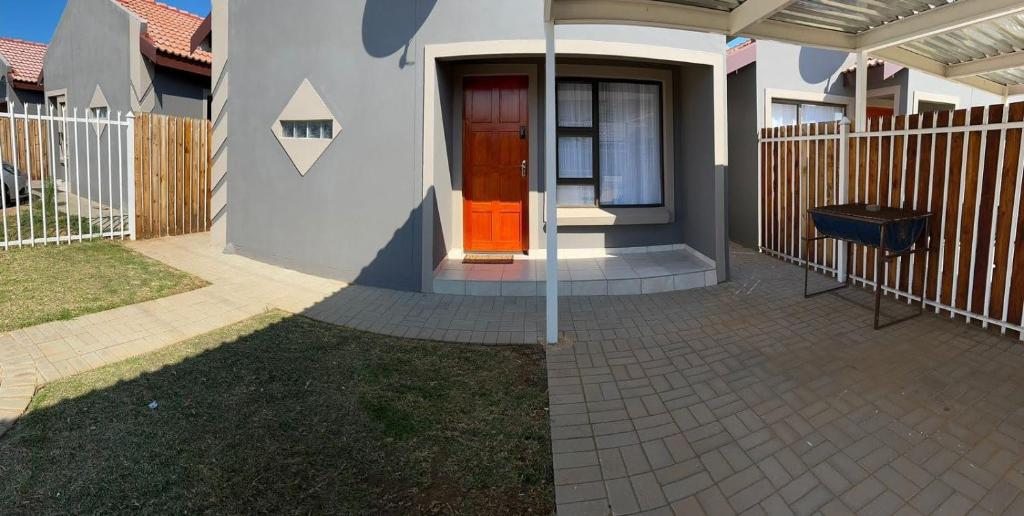 uma casa com uma porta vermelha e uma cerca em MV self-catering Linden em Bloemfontein