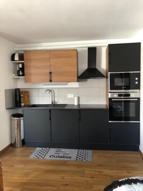 a kitchen with black and white cabinets and a sink at location studio de 2 - 4 personnes in Hautecour