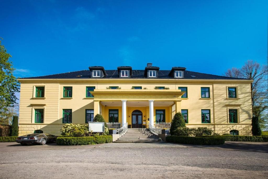 une grande maison jaune avec un escalier en face de celle-ci dans l'établissement Schloss Harkensee, à Dassow