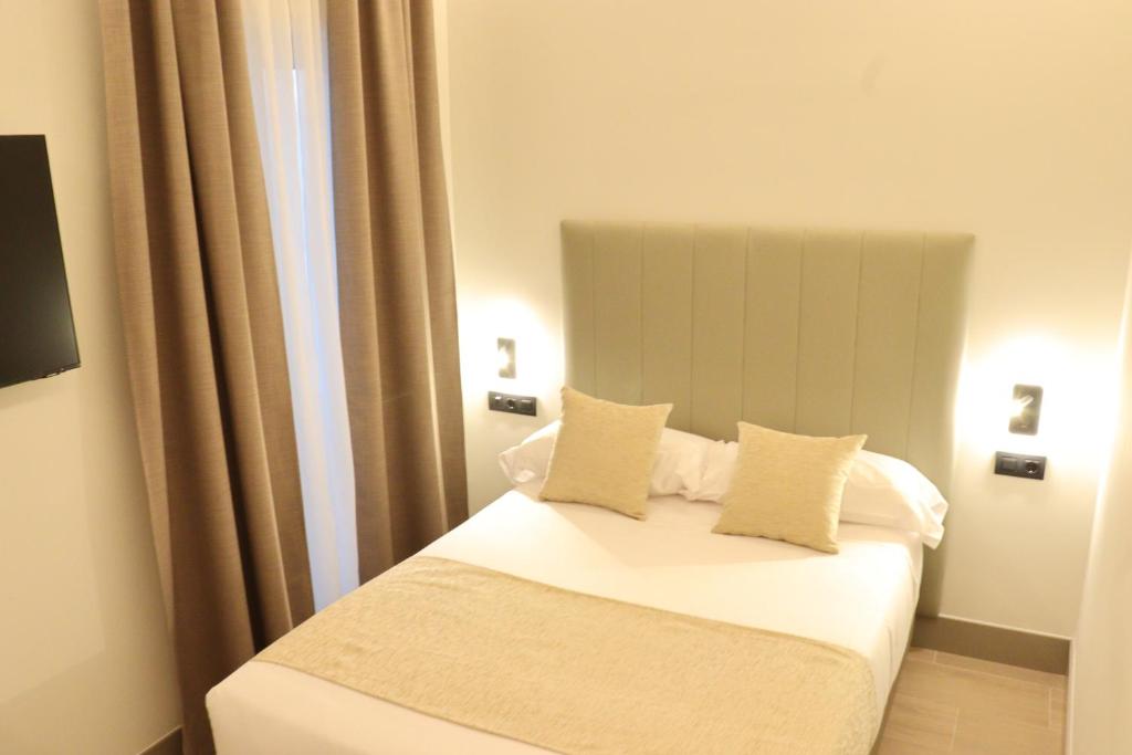 a bedroom with a bed with white sheets and pillows at Hostal La Rúa-Montera in Madrid