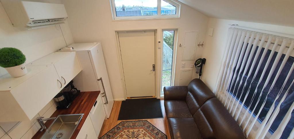 a living room with a leather couch and a window at Smakfullt attefallshus med stort loft nära naturen in Stockholm