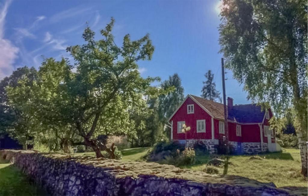a red house sitting next to a stone wall at Gorgeous Home In Lnsboda With Lake View in Lönsboda