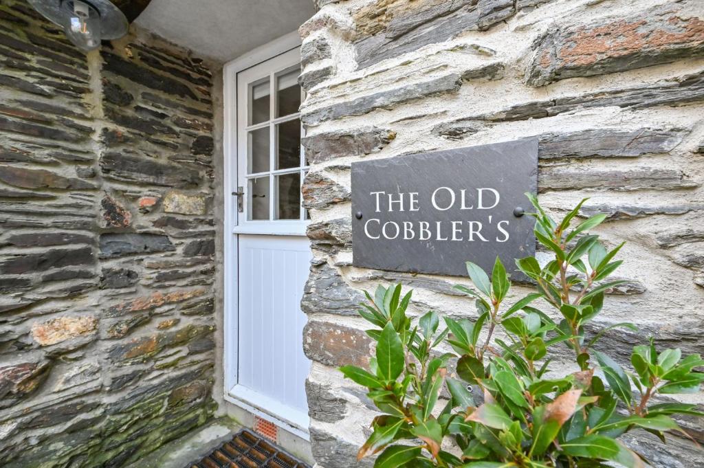 a sign on the side of a stone building with a window at Old Cobblers in Port Isaac