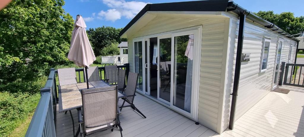 an outdoor deck with chairs and an umbrella at Beautiful Caravan With Decking Wifi At Isle Of Wight, Sleeps 4 Ref 84047sv in Porchfield