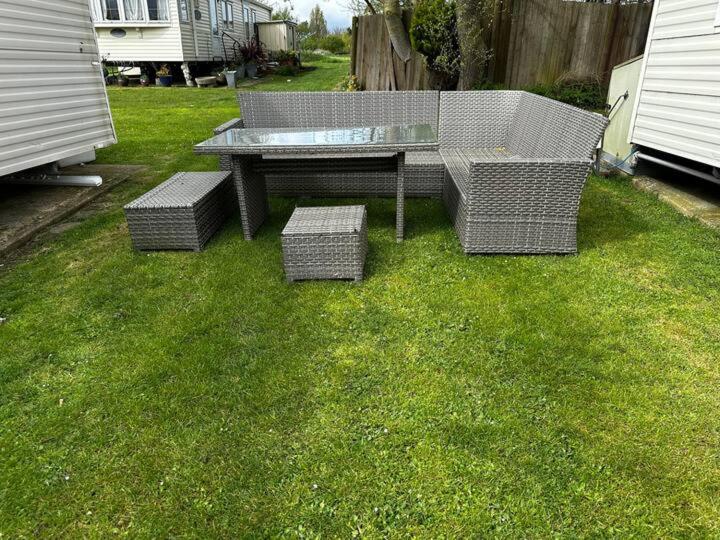 a picnic table and four benches in the grass at 2 bedroom caravan, sea views, parking in Eastchurch