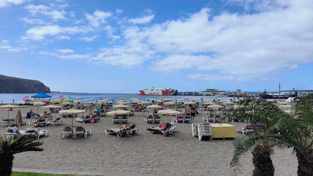 una spiaggia con molte sedie e ombrelloni sulla sabbia di Apartamento en Los cristianos 2 habitaciones 4 huespedes Vv Elenita a Los Cristianos