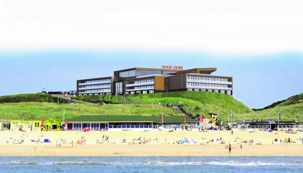 un hotel en una playa con gente en la playa en Strandhotel Het Hoge Duin, en Wijk aan Zee