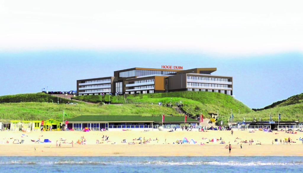 un hôtel sur une plage avec des gens sur la plage dans l'établissement Strandhotel Het Hoge Duin, à Wijk aan Zee