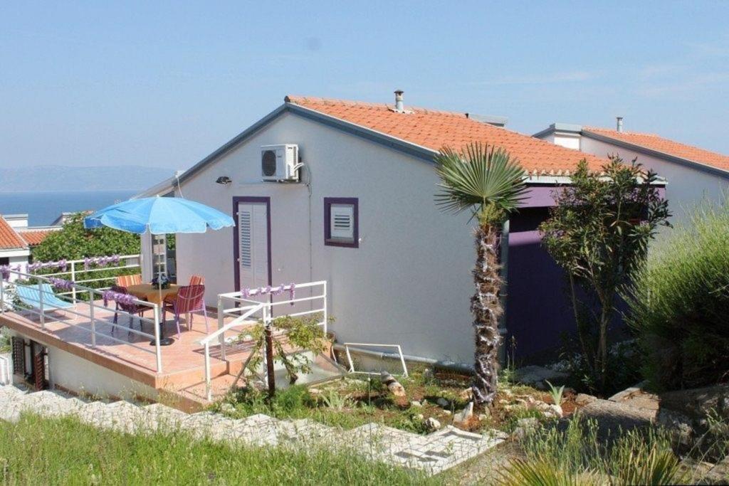 une petite maison avec une terrasse et un parasol dans l'établissement Ferienwohnung für 5 Personen ca 45 qm in Skvaranska, Istrien Bucht von Raša, à Ravni
