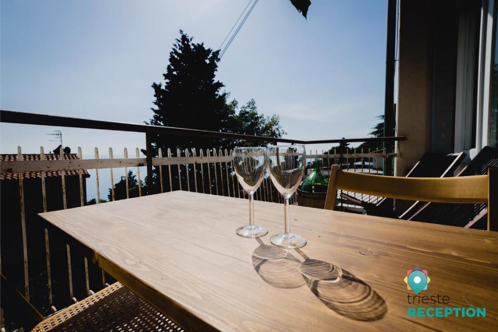 2 bicchieri da vino seduti su un tavolo di legno sul balcone di Sea Breeze - Barcola a Trieste