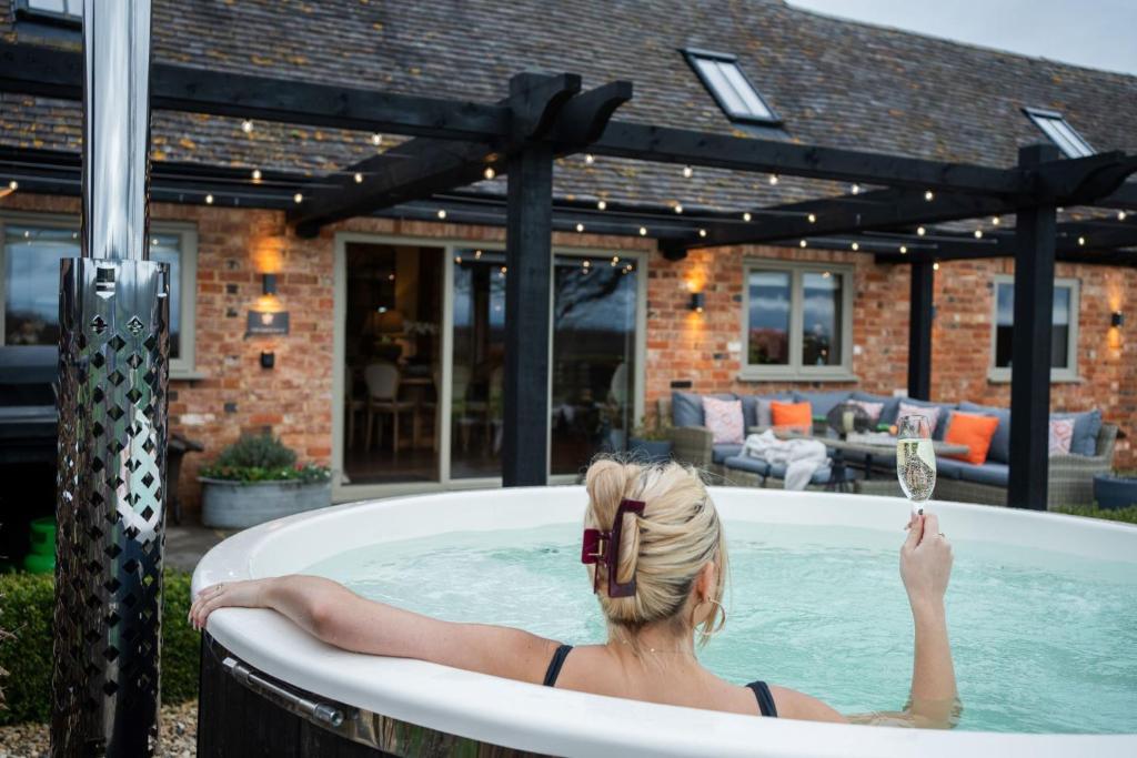 a woman in a bath tub with a glass of wine at The Carriage House in Stratford-upon-Avon