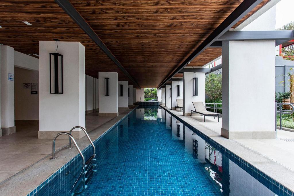 an indoor swimming pool with a wooden ceiling and blue water at Is Moema in Sao Paulo