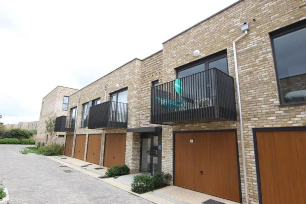 a brick building with brown doors and balcony at 5* Cambridge Boutique Apartment in Trumpington