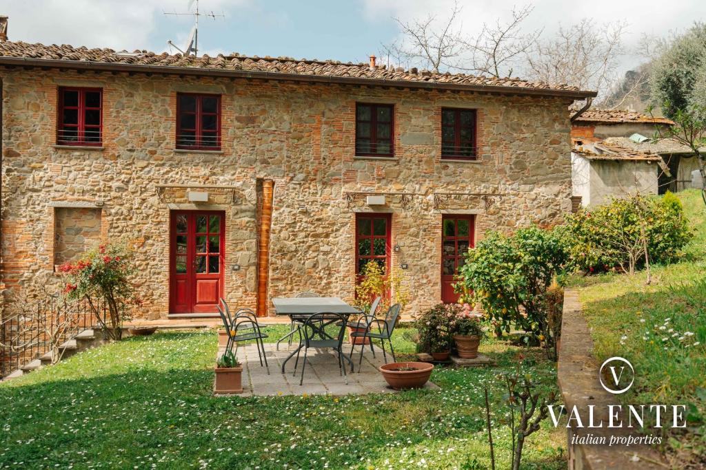uma casa de pedra com uma mesa e cadeiras em frente em Casa con vista panoramica, Matraia, Lucca em Matraia