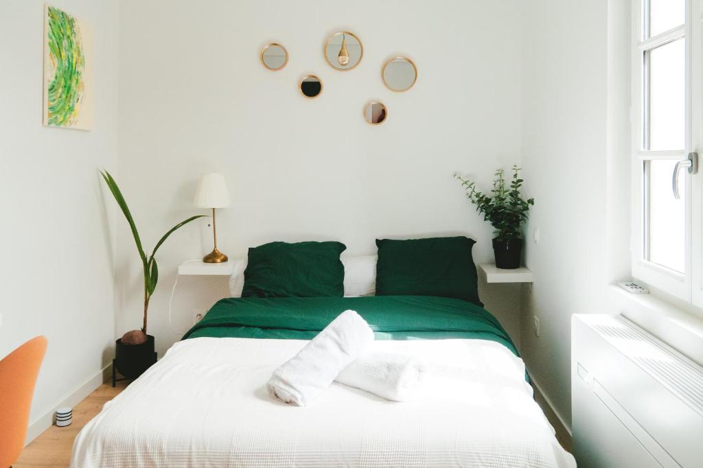 een wit en groen bed in een witte kamer bij ô Quai St Pierre in Toulouse