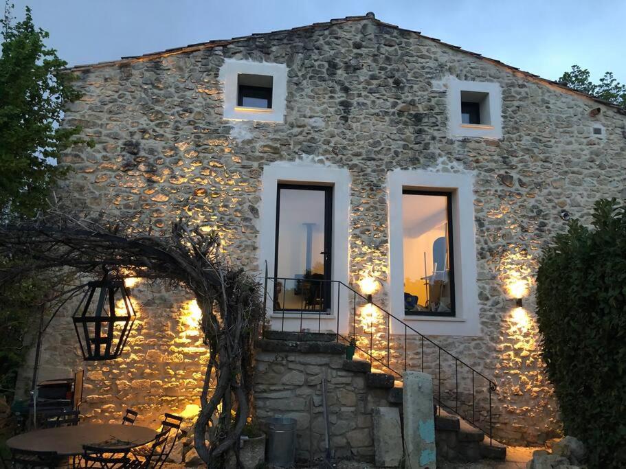 - un bâtiment en pierre avec une table devant dans l'établissement Charmant moulin en pierre, à Saint-Pierre-de-Vassols