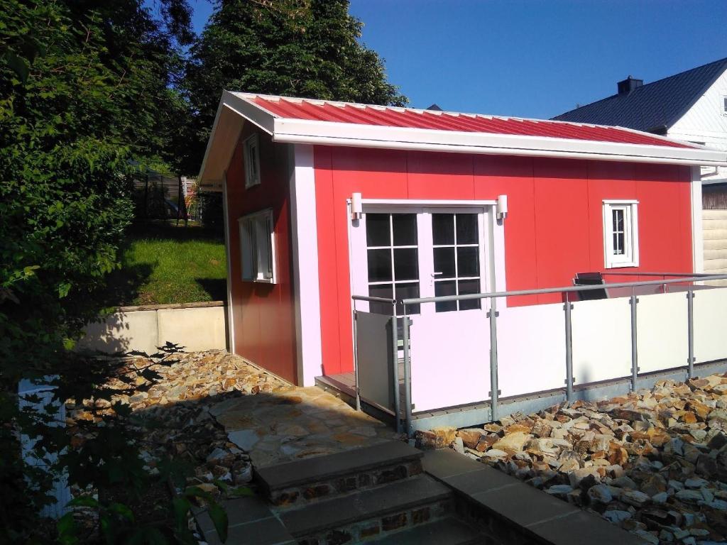 een klein rood-wit gebouw met een deur bij Ferienhaus in Bad Marienberg Westerwald mit Grill und Terrasse in Bad Marienberg
