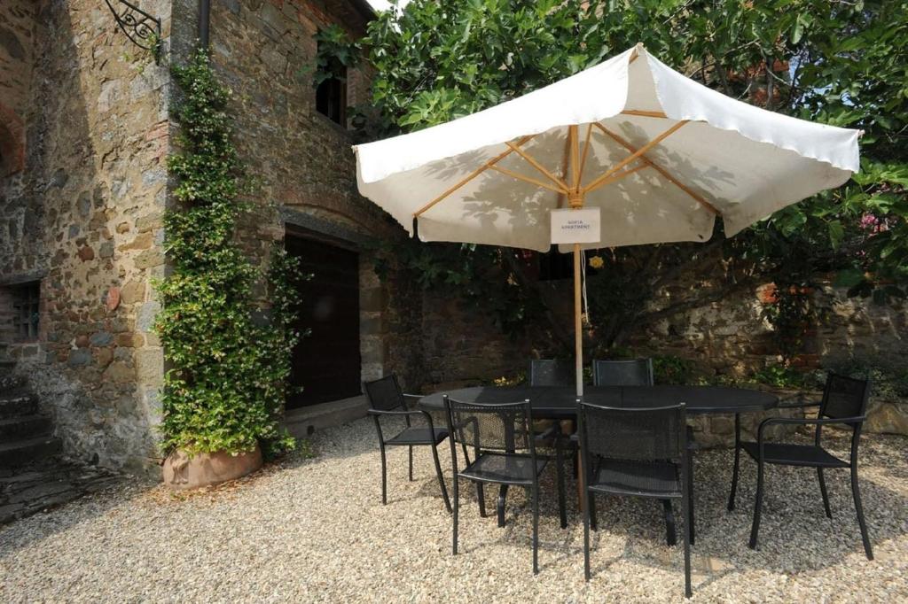 a table with an umbrella in front of a building at Große Ferienwohnung in Rapale mit Terrasse, gemeinsamem Pool und Grill und Panoramablick in Rapale
