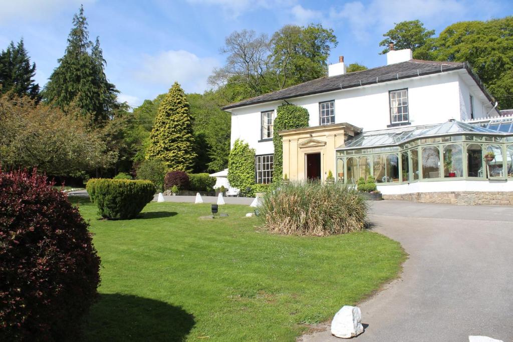 a white house with a conservatory in a yard at Harrisons Hall Bed & Breakfast in Mold