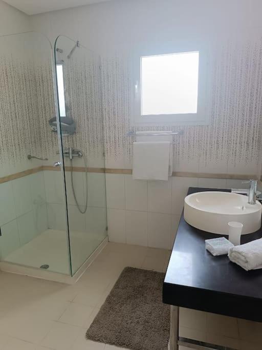 une salle de bain avec une douche en verre et un lavabo dans l'établissement Logement S+2 dans un hôtel 4* vue mer, à Bizerte