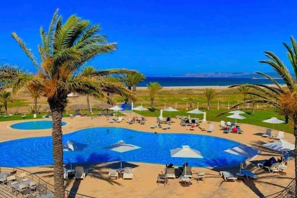 een resort met een groot zwembad en palmbomen bij Logement S+2 dans un hôtel 4* vue mer in Bizerte