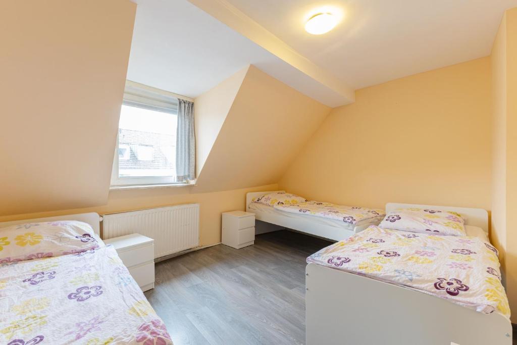 2 łóżka w pokoju z żółtymi ścianami i drewnianą podłogą w obiekcie Messe Monteurzimmer Köln w Kolonii