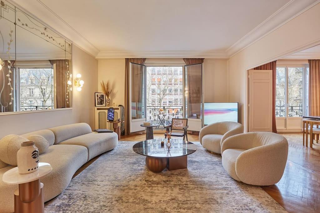 uma sala de estar com um sofá e cadeiras e uma televisão em Apartment Arc de Triomphe/ Champs Elysée by Studioprestige em Paris