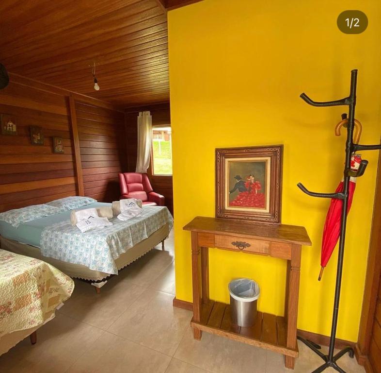 1 dormitorio con cama y pared amarilla en Pousada valle do chalé, en Capitólio
