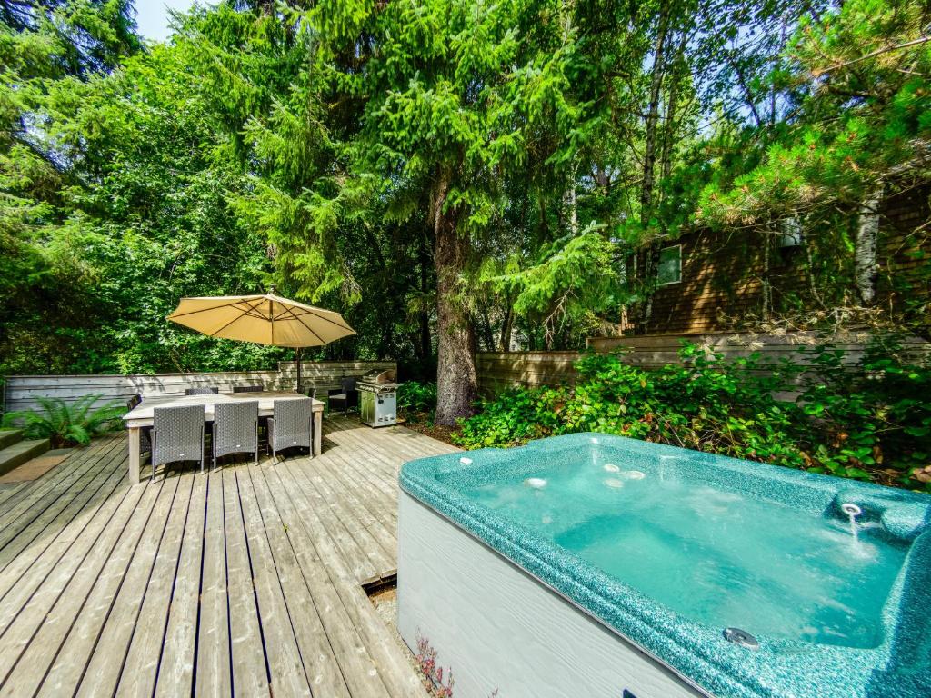 a hot tub on a deck with a table and an umbrella at Bella Mar in Nehalem