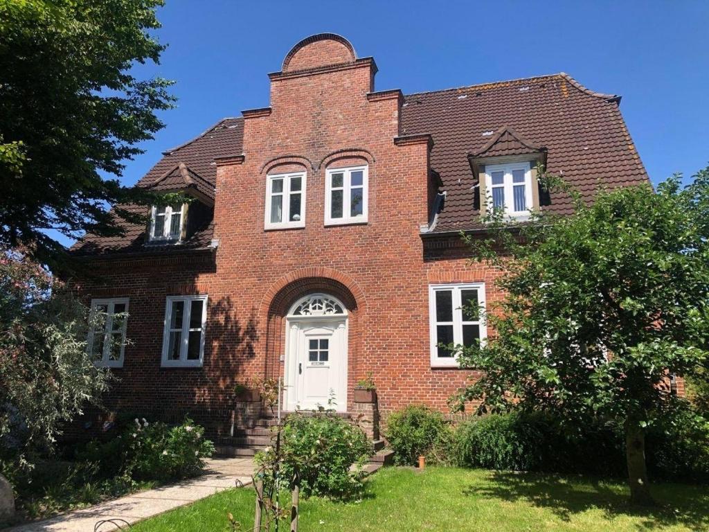 une ancienne maison en briques rouges avec une porte blanche dans l'établissement Das Künstlerhaus, à Niebüll