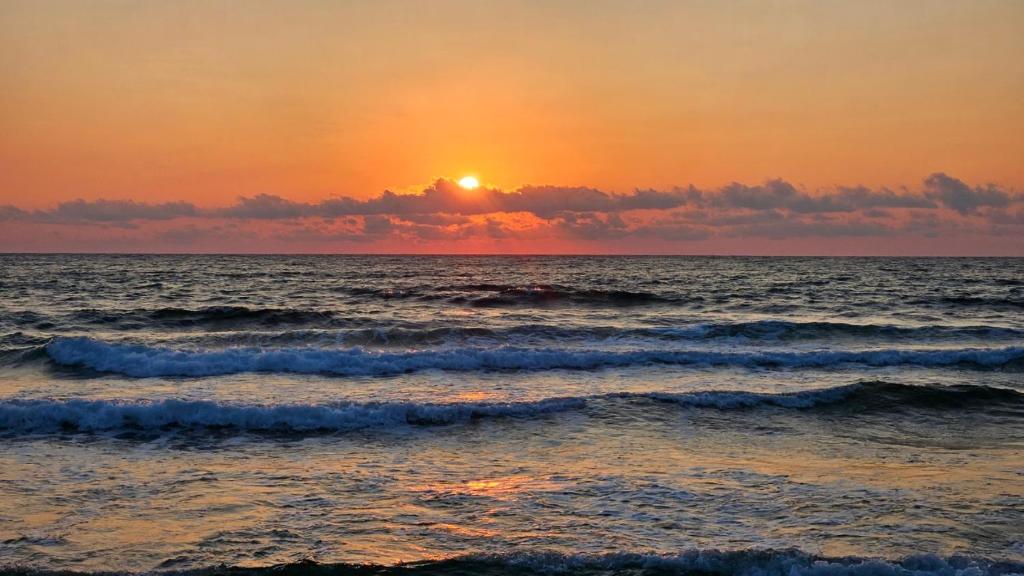 a sunset over the ocean with waves at Sea and Sand Apartment Greenn Life in Sozopol