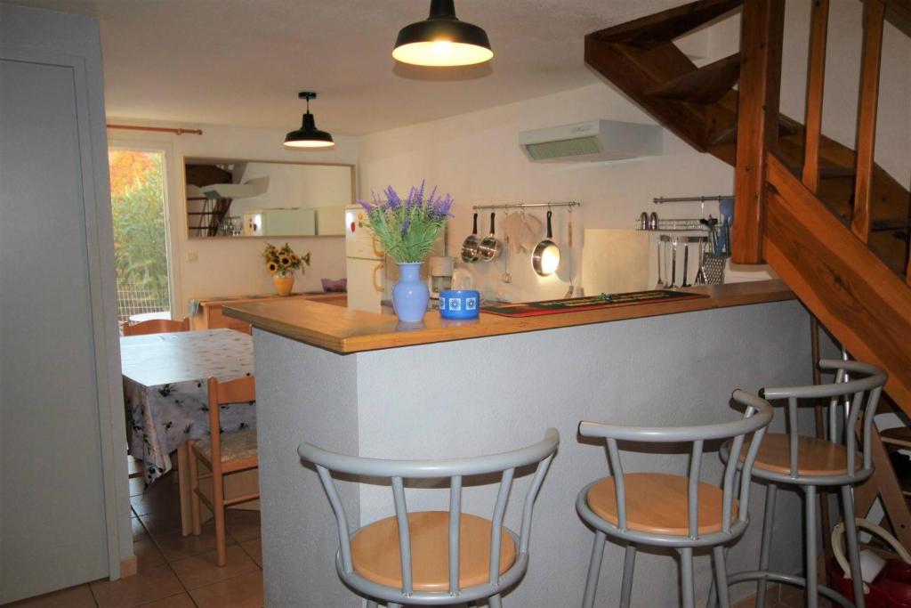 une cuisine avec trois tabourets de bar à un comptoir dans l'établissement Belle villa entièrement climatisée 4 chambres 10 couchages, fibre WIFI, 2 terrasses parking privatif dans résidence sécurisée piscine commune 800 m de la mer LRCS69, à Portiragnes