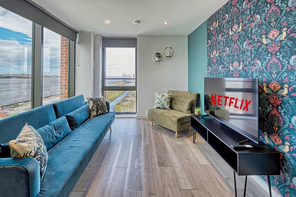 een woonkamer met een blauwe bank en een televisie bij Ultimate Escape - Great View in Liverpool