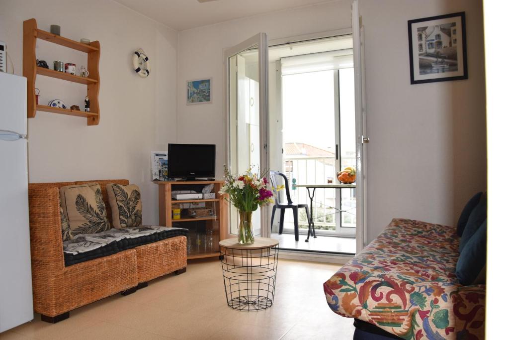 uma sala de estar com um sofá e uma mesa com um vaso de flores em Appartement 1 chambre, avec loggia et vue sur le Port Olona em La Chaume