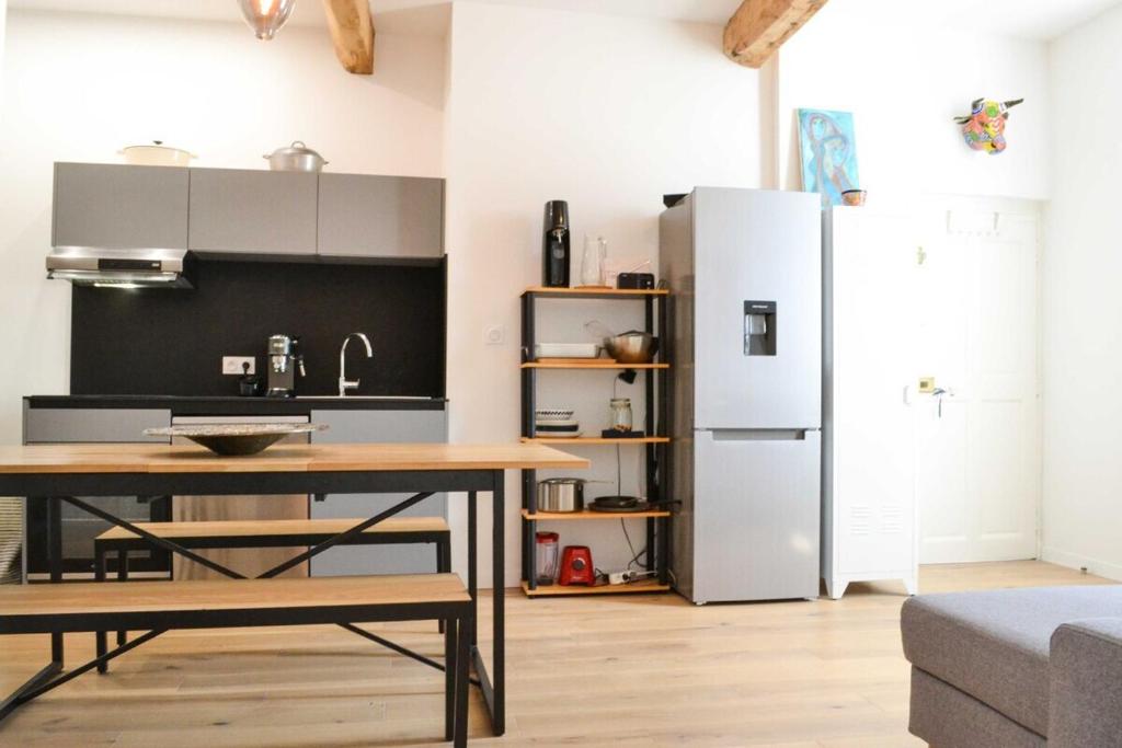 une cuisine avec une table et un réfrigérateur dans l'établissement Le Cabanel - Climatisation en centre ville, à Montpellier