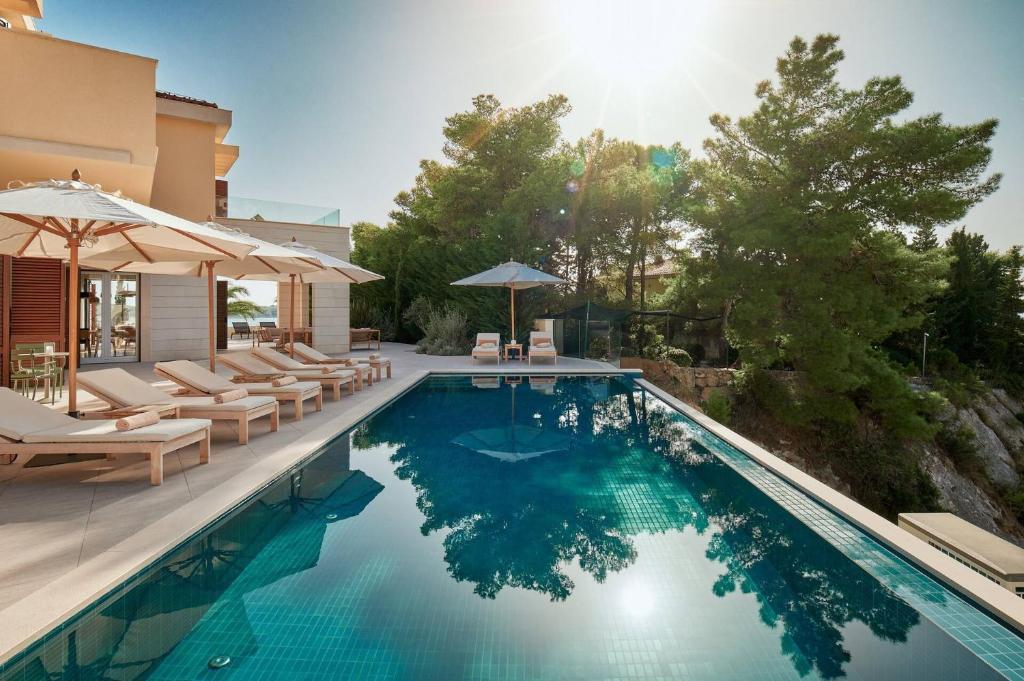 赫瓦爾的住宿－Beautiful Villa Crystalsea 2 with a pool in Hvar，房屋旁的游泳池配有椅子和遮阳伞