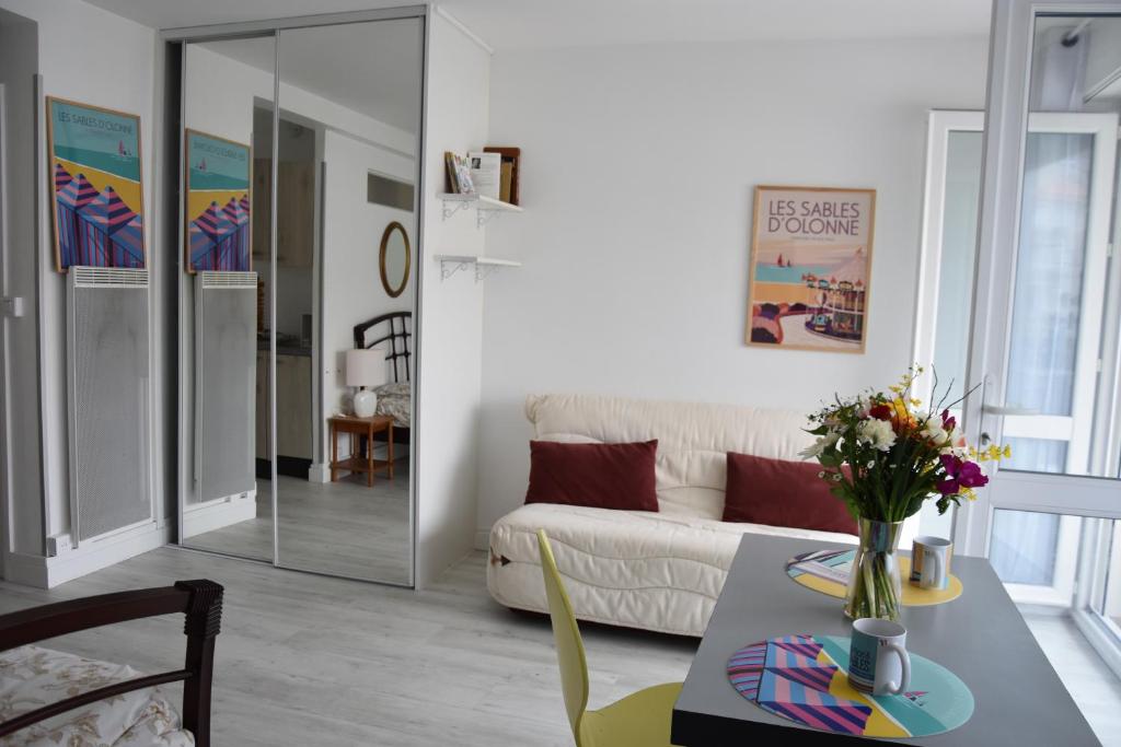uma sala de estar com um sofá e uma mesa com flores em Les Grandes Roches - Studio et balcon plage à pied em La Rudelière
