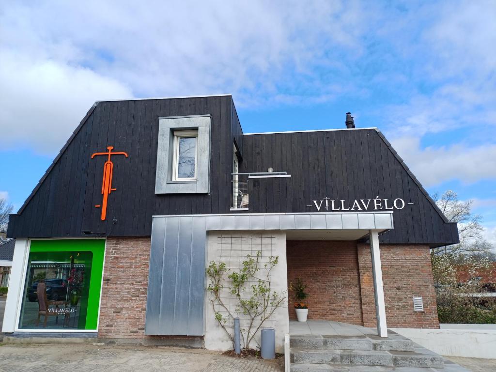 Una iglesia con un techo negro con una cruz. en Villavelo Twente, en Ootmarsum