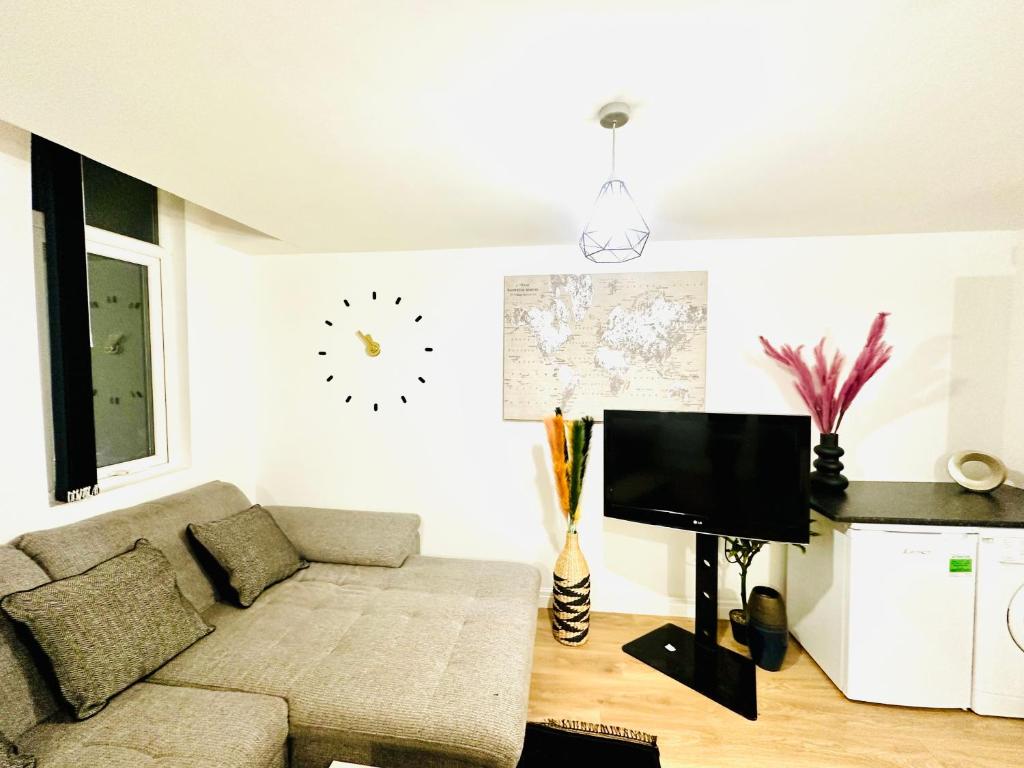 a living room with a couch and a clock on the wall at Albert Inn Apartments in Manchester