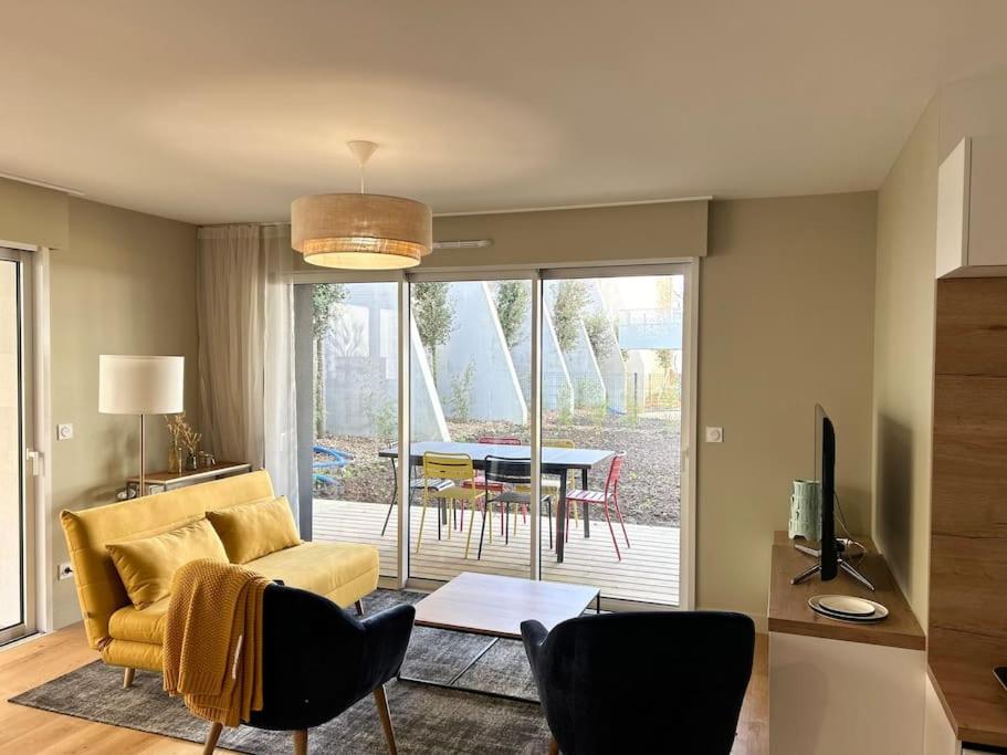 un salon avec un canapé jaune et une table dans l'établissement Appartement centre avec jardin-400m plage, à Concarneau