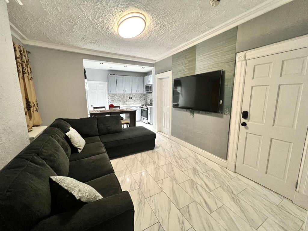 uma sala de estar com um sofá preto e uma televisão de ecrã plano em 3 bedrooms in Modern Brooklyn home, Close to J train em Brooklyn